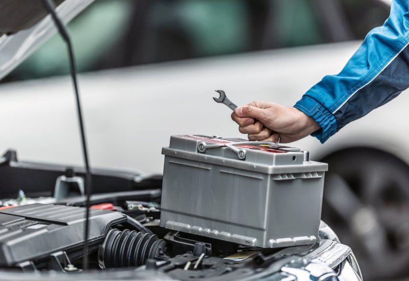 Mechanic,Holds,Key,Over,Car,Battery,With,Engine,Trunk,Of